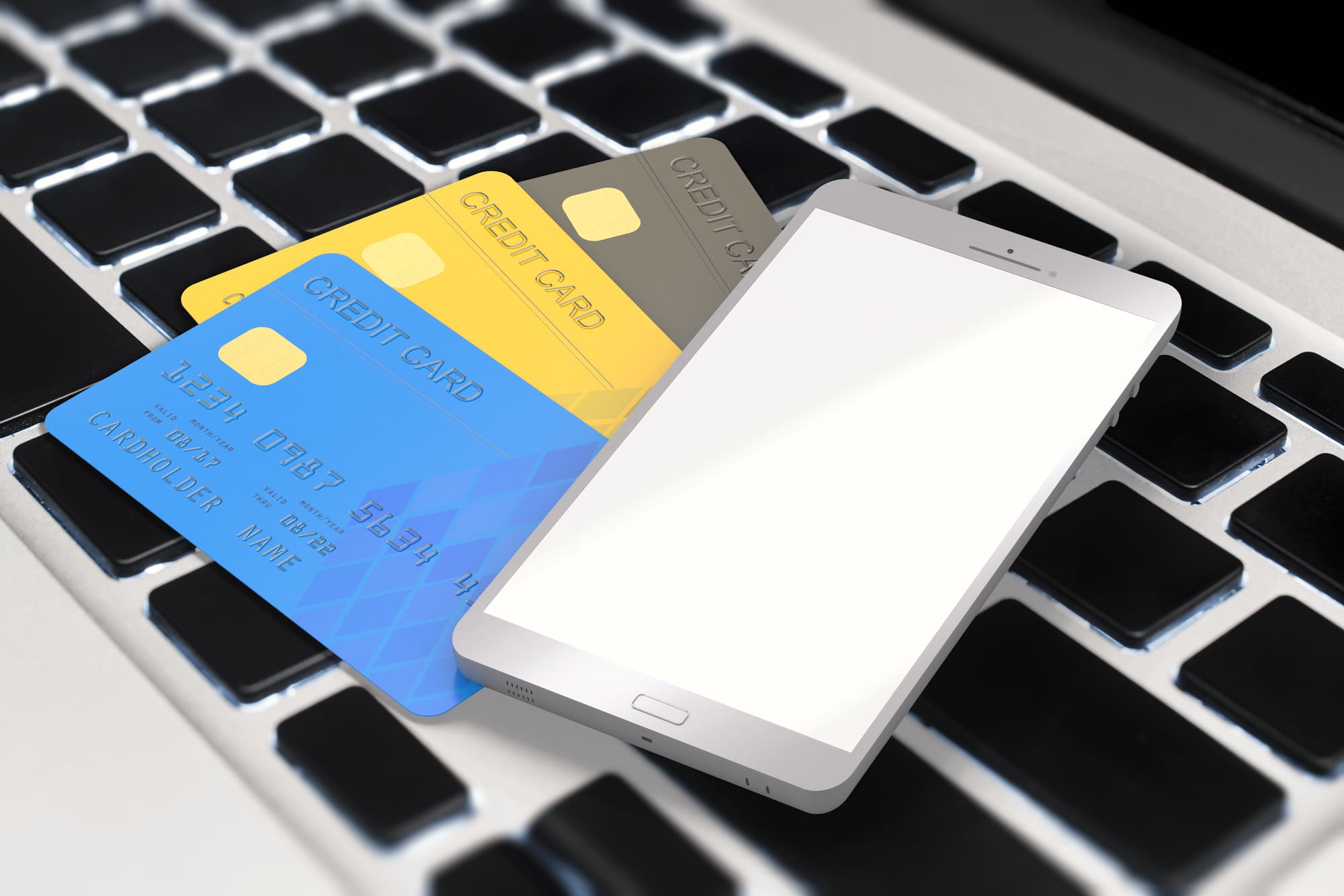 パソコンの上にクレジットカードとスマートフォンが乗っている